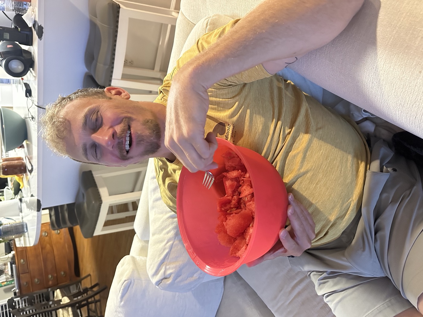 Jared on the couch grinning with a mixing bowl full of watermelon