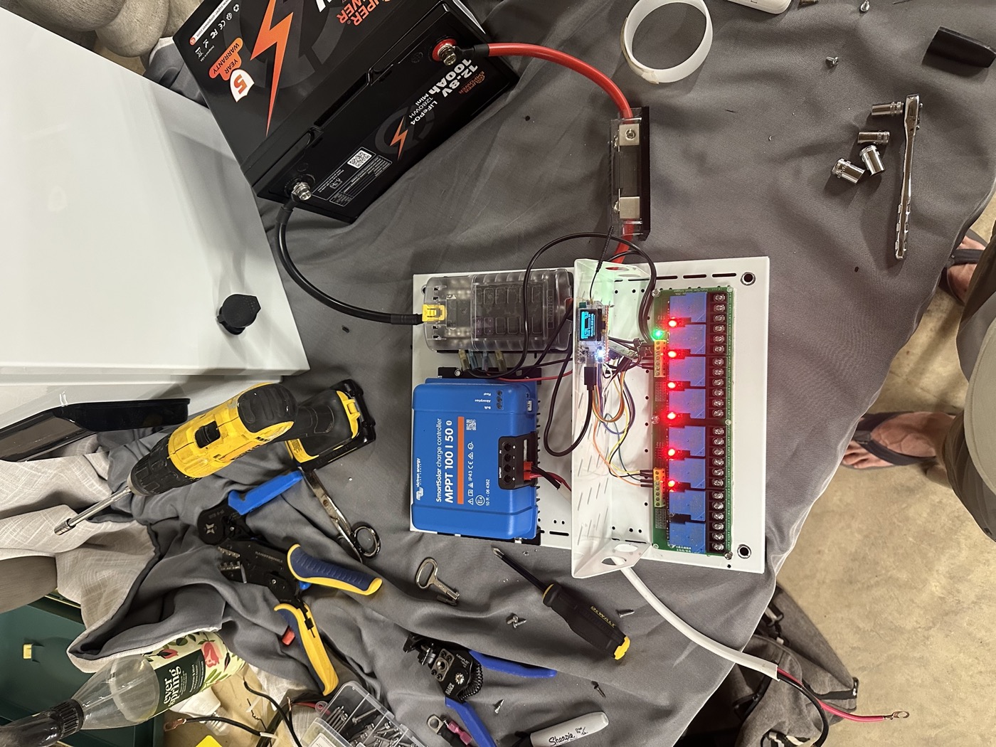 Workbench with a lithium battery, Victron solar charge controller, relay board, and wiring mid-assembly